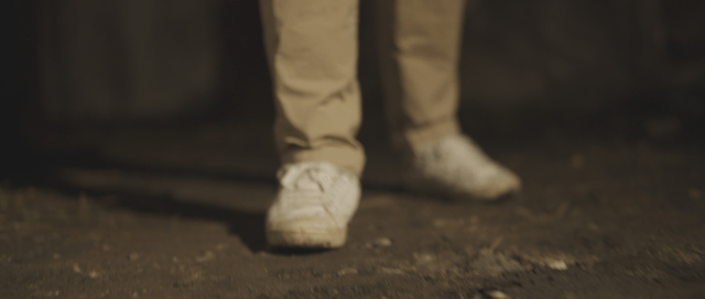 Person staggering on a dirt ground at night