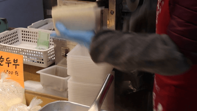 Person packaging tofu at a market