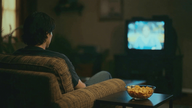 Person preparing snack and watching TV in dark living room