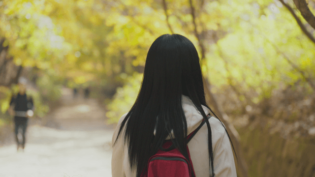 Long-haired woman descending autumn mountain trail