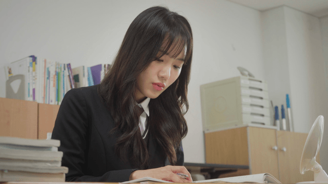 긴 웨이브 머리의 여학생이 교실에서 공부하는 모습
