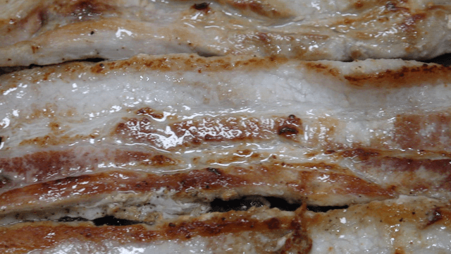 Grilled pork belly sizzling on a pan