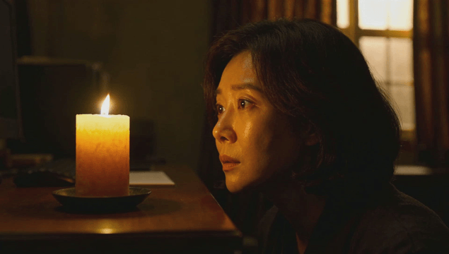 Frightened woman staring at candle in dark room