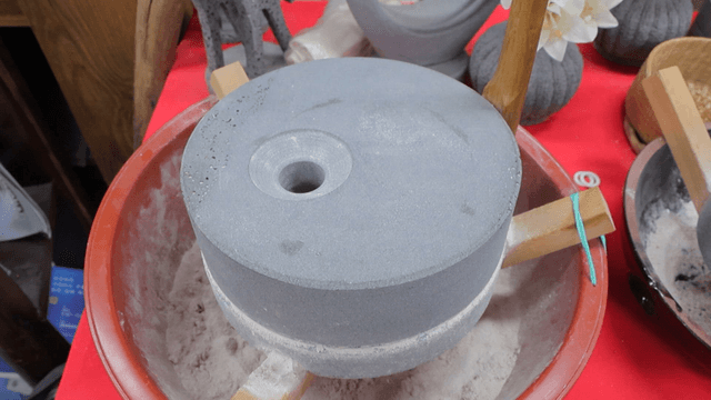 Traditional basalt millstone on a red container