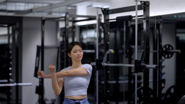 Young woman stretching arms at gym