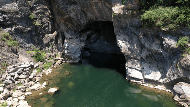 Clear stream flowing below steep cliff