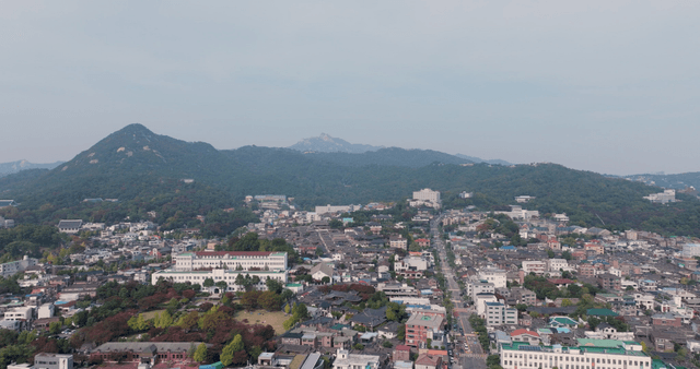 고지대 배경의 한옥 마을과 현대 주택가 풍경