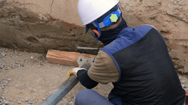 Worker securing pipes at a construction site