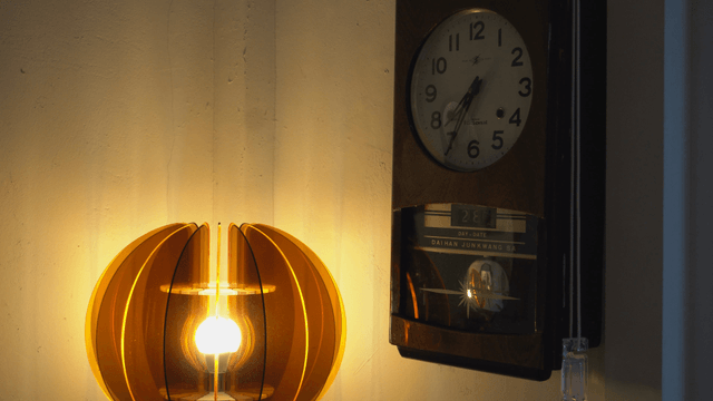 Vintage clock and modern lamp on wall
