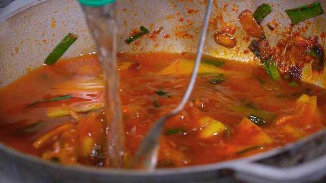 Adding water to stir-fried vegetables with seasoning