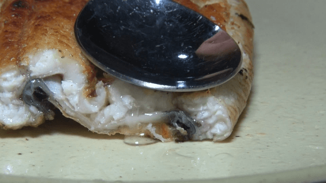 Spoon pressing out the juice of grilled eel