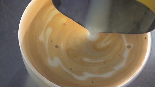 Milk being poured into a cup of coffee