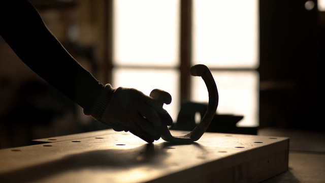Woodcraft artisan placing a half-round sculpture on the workbench