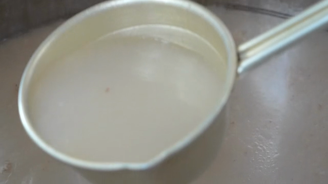 Ladle scooping broth from a large pot