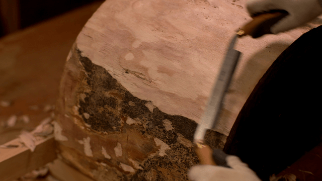 Woodcraft artisan trimming wooden surface with sickle knife