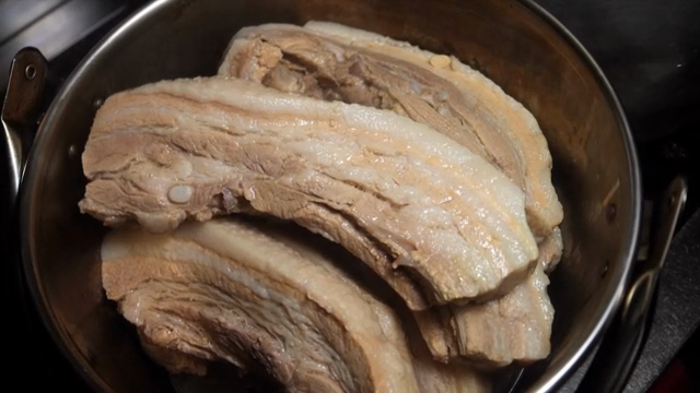 Boiled pork being transferred into a pot
