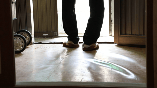 Elderly person entering a room wearing slippers