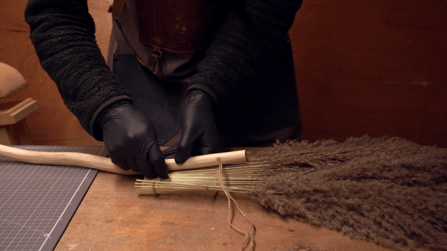 Person crafting a handmade broom indoors
