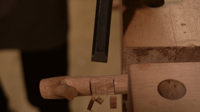 Hands delicately carving wood with a chisel
