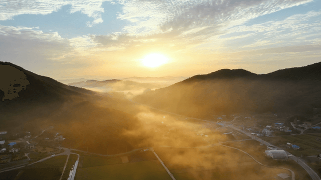 Sunrise over misty mountains and fields