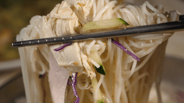 Chopsticks holding noodles with vegetables
