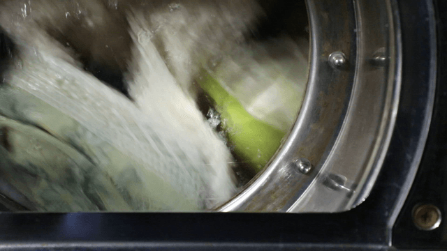 Clothes spinning inside a laundromat washing machine
