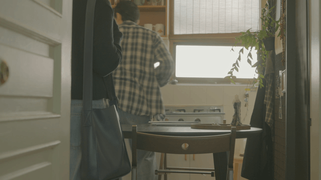 Man in check shirt taking pot for guests in kitchen