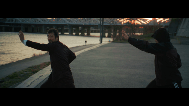 Two people practicing traditional martial arts by the river