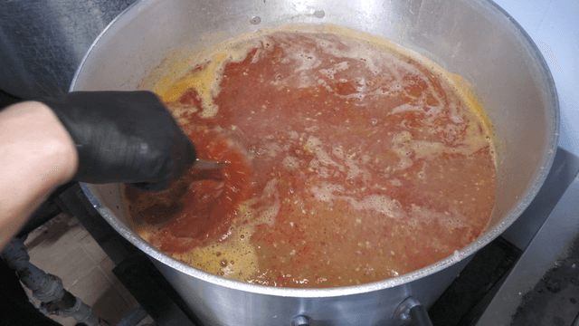 Red broth stirred in a large pot