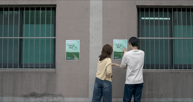 Two people posting poster on wall