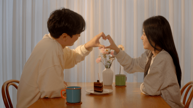 Couple greeting and making heart shape at dining table