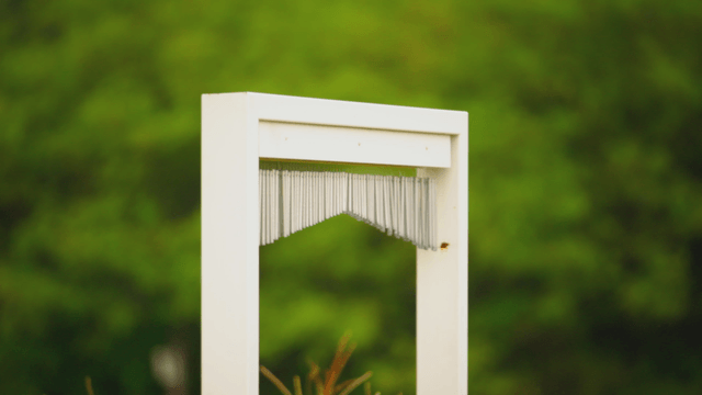 Wind chime in front of a green garden view
