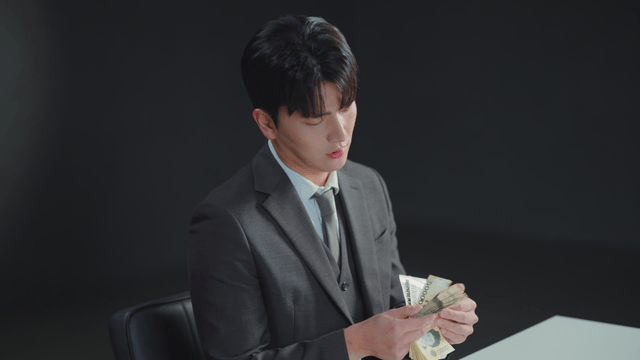 Man in a suit counting money at a desk