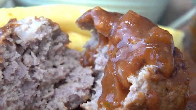 A scene where sauce is put on top of a hamburger steak