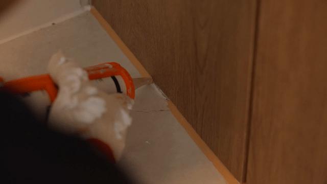 Worker finishing wall corner with sealant gun