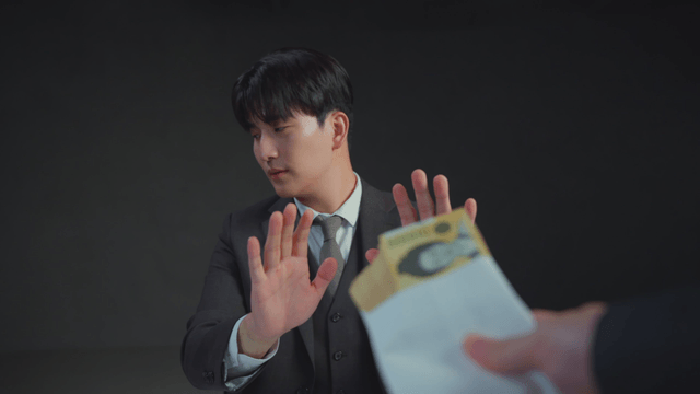 정장을 입은 남자가 봉투를 거절하는 모습