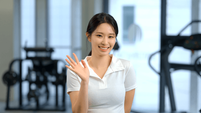 Smiling woman waving forward in a gym