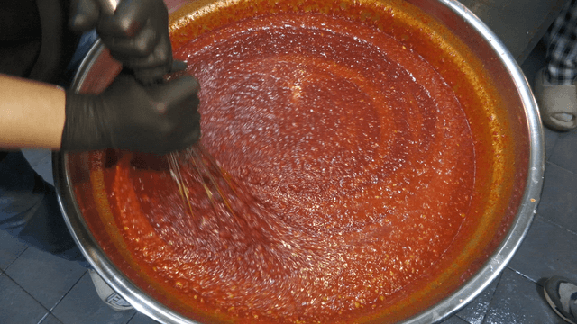 Mixing red sauce in a large pot