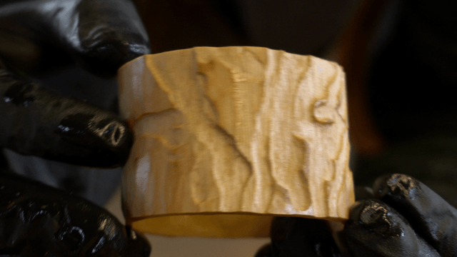 Gloved hand examining a piece of wood