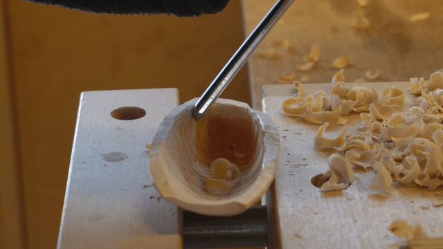 Gloved hands carving wood on the workbench