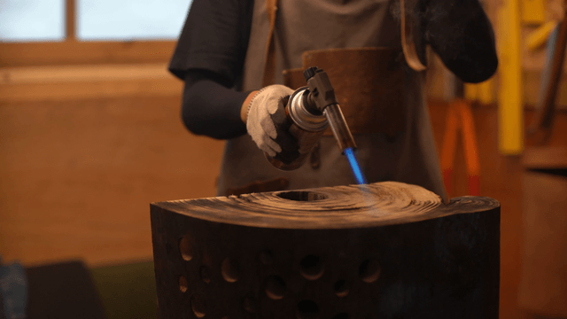 Woodcraft artisan using a torch on wooden sculpture