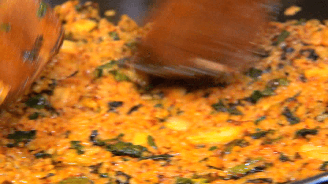 Glossy fried rice spread flat with spatula on iron plate