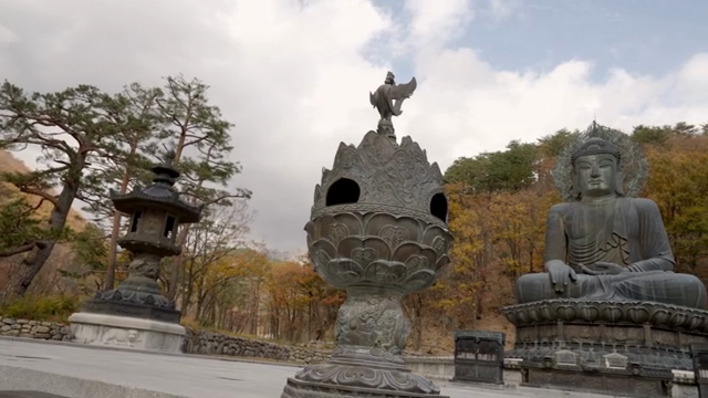 Woman viewing a large Buddha statue in a quiet mountain