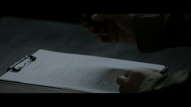 Person writing on a document in a dim room