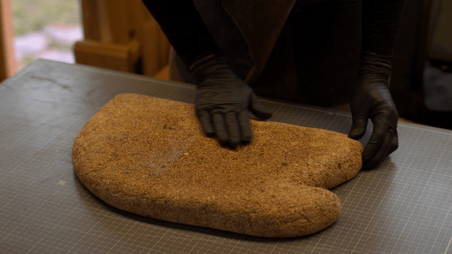 Artisan applying finishing solution to cork sculpture