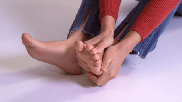 Person sitting cross-legged massaging foot