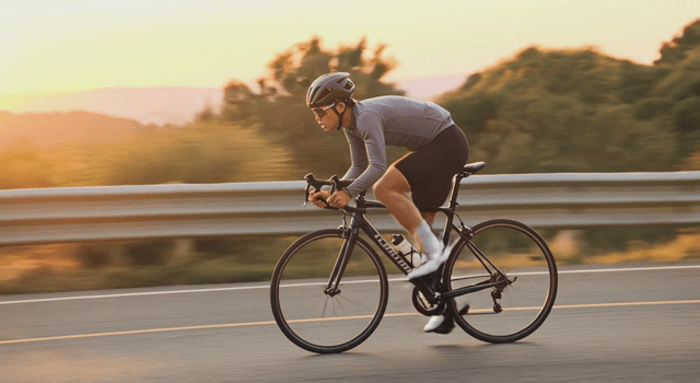 Cyclist riding on a road during sunset