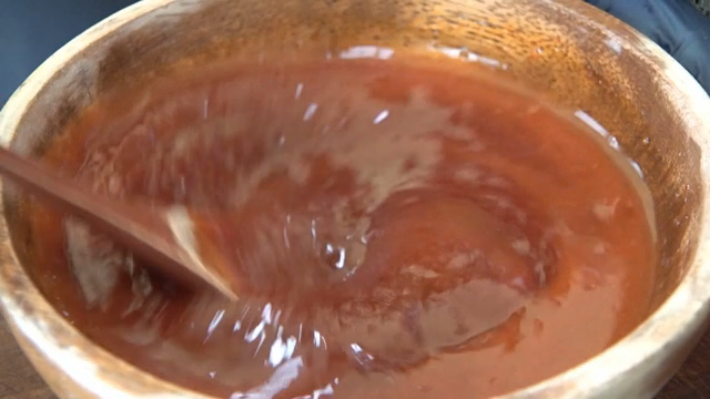 Mixing red sauce in a wooden bowl