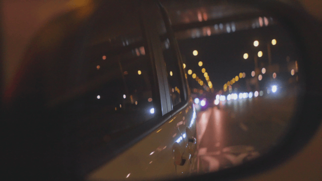 Night view of the road seen through a side mirror