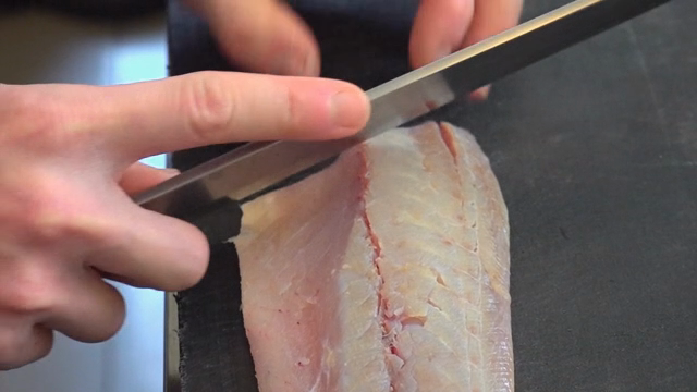 Slicing raw mackerel on a cutting board